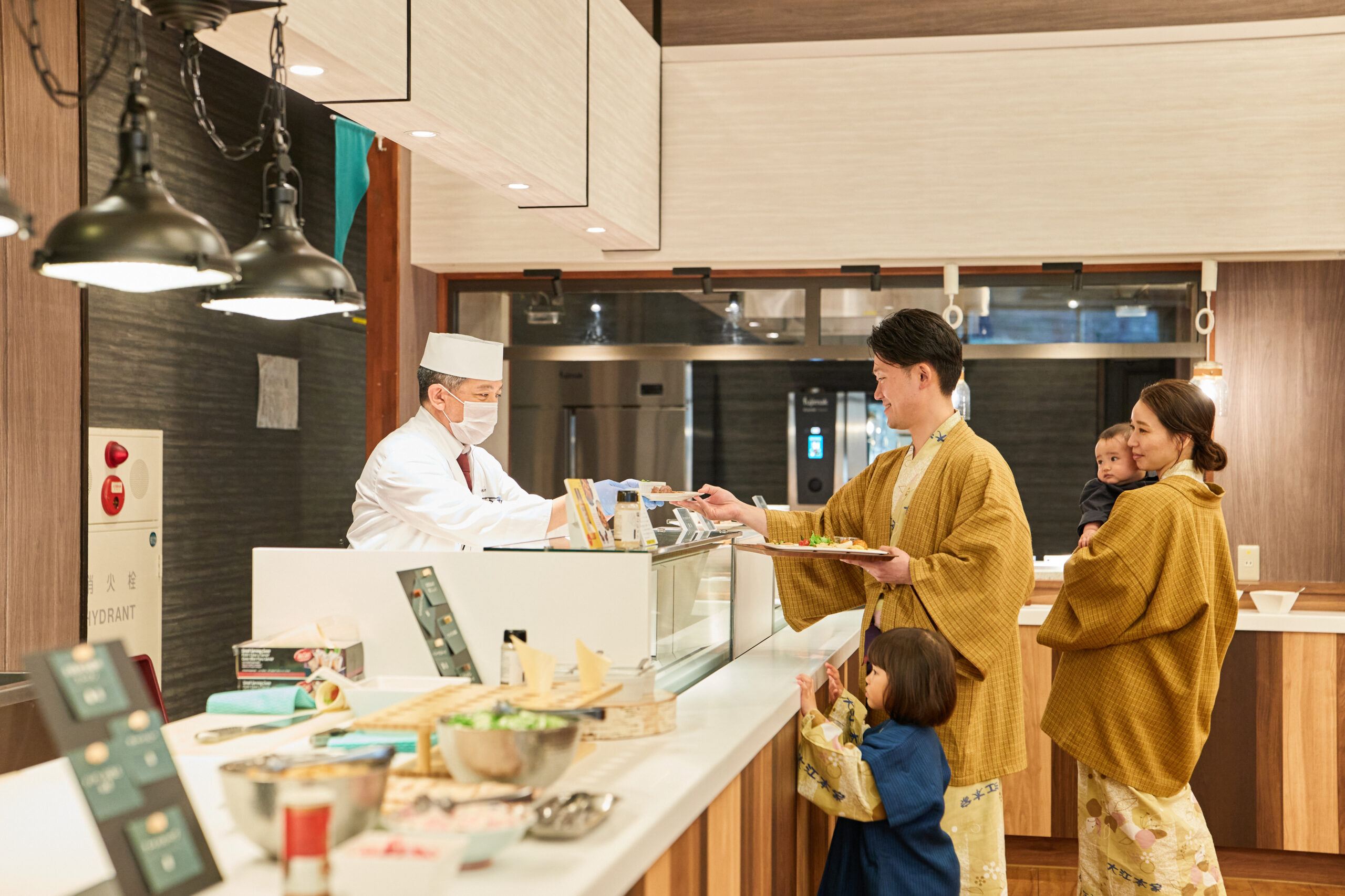 大江本家のライブキッチンで料理を受け取るご家族